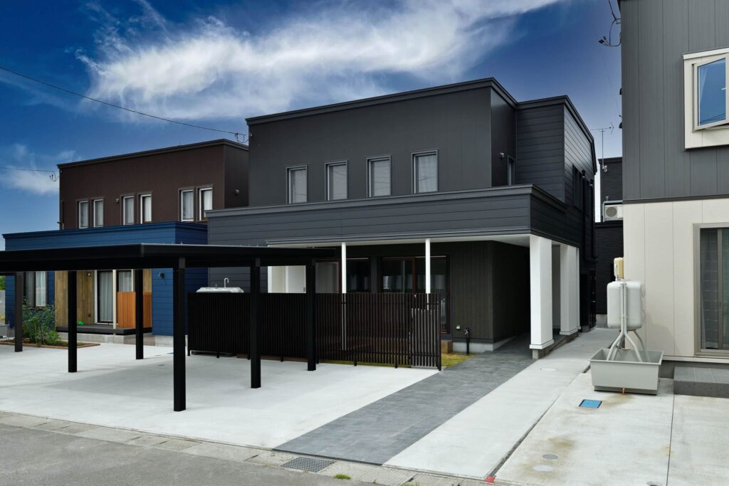 黒い外壁と片流れ屋根の K邸 外観。カーポートと前面道路が写る